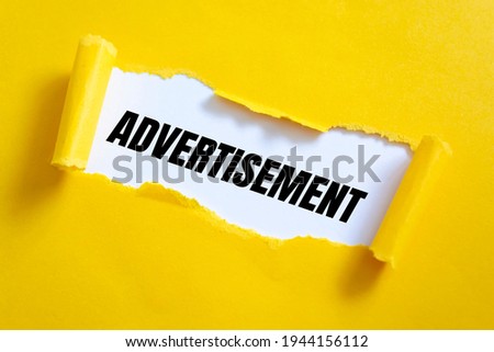 Torn yellow paper on white surface with Advertisement words.