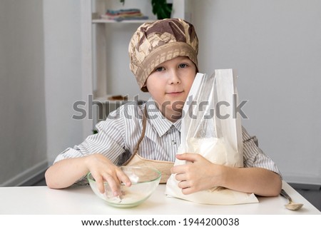 A boy of 7-8 years prepares dough for cookies.