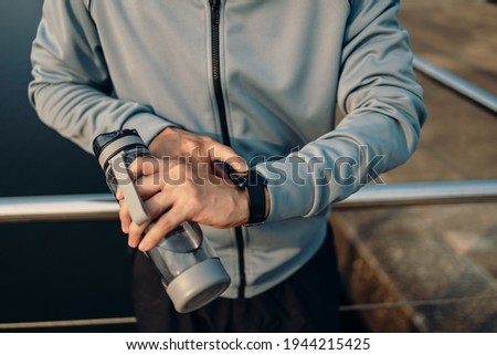 sport man checking at smartwatch during training and running in the park.  Royalty-Free Stock Photo #1944215425
