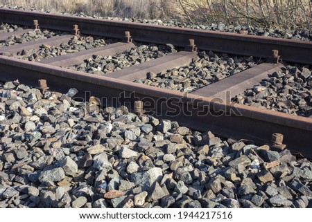 A shot of rusty metal train tracks surrounded by rocks 