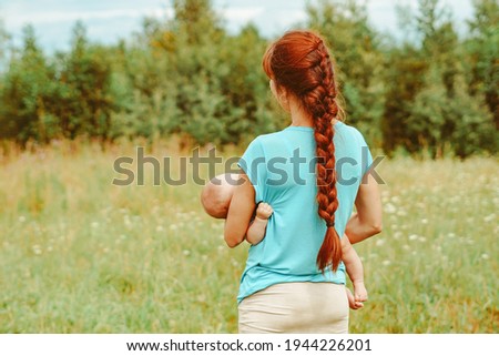 Beautiful mother and her little daughter are outdoors cuddling sitting on the grass