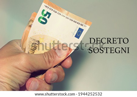 Hand holding banknotes with the sign "Decreto Sostegni" translated in financial help. Incentive from the italian government.