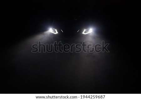 The headlights of the car, the rays of light make their way through the fog of the night Royalty-Free Stock Photo #1944259687