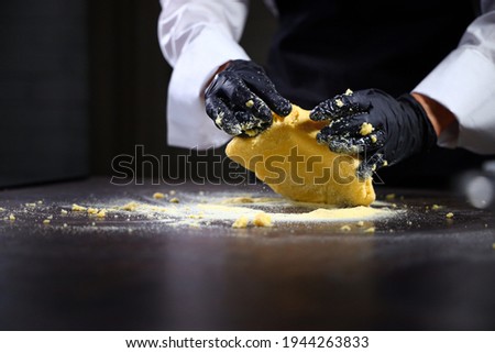 A cook in black gloves kneads the dough. Corn flour dough. Gluten-free product.Healthy food. An unrecognizable person. Bottom view. Free space.