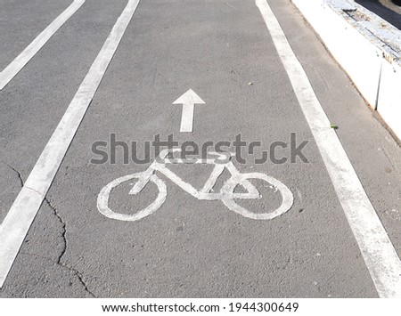 Bicycle path sign hand-painted on asphalt. The track itself is visible. In the city.