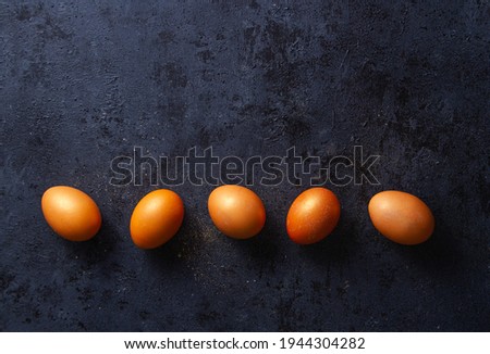 Orange golden glitter eggs on dark blue background with texture, row, free space