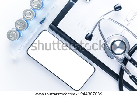 Medical equipment. Doctor stethoscope, healthcare charts, syringe with needle and black smartphone with blank screen on hospital equipment background. For design application, website project