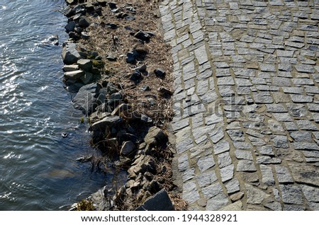 edge of the river bank reinforced with giant stones as a breakwater against erosion of stone paving at the dock cobblestone promenade