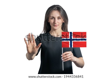 Happy young white woman holding flag of Norway and with a serious face shows a hand stop sign isolated on a white background.