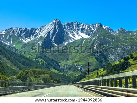 A beautiful view of a straight paved road winding through a forested mountain range in Switzerland