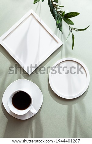 White blank round and square photo frames and white cup of black coffee on a green pastel background. Poster mockup with romantic long shadows.