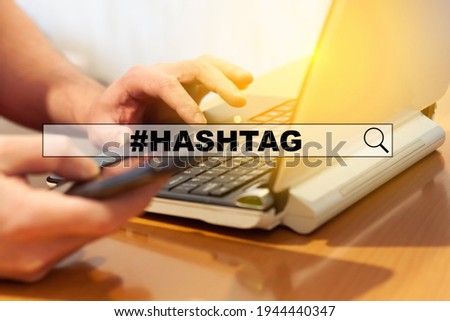 A man using a smart phone and laptop, writes a hashtag in an Internet search. Hashtag concept.