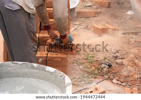 Construction workers use tools to cut bricks.