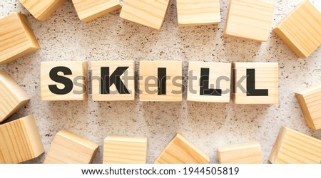 The word SKILL consists of wooden cubes with letters, top view on a light background. Work space.