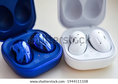 Wireless headphones of different colors in a case on a white background. Royalty-Free Stock Photo #1944511108