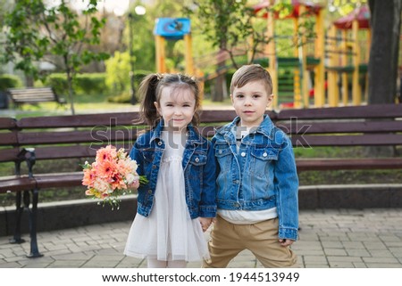 Little girl and boy in the park with a bouquet of flowers.