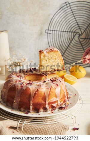A vertical shot of a delicious citron cake with a cut piece with glaze and flower on top on a table