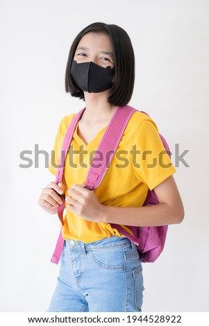 Young girl hold notebook wear black mask on white background.