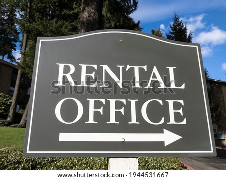 Street view of a sign pointing out the direction of an apartment rental office in a large community