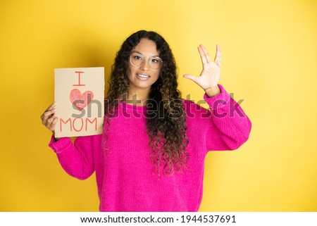 Beautiful woman celebrating mothers day holding poster love mom message doing hand symbol