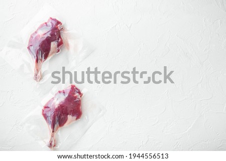 Vacuum packed raw duck leg set, on white stone background, top view flat lay, with copyspace and space for text