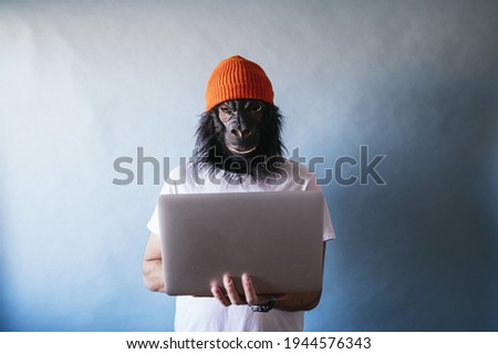 A male in a chimpanzee mask using a laptop
