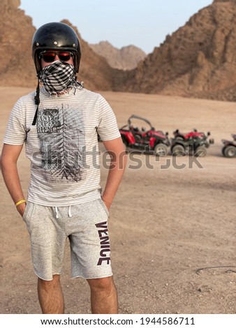 buggy safari.man in helmet with glasses and arafat in the desert.arafat man in the desert.Young Man in buggy during safari trip in desert.