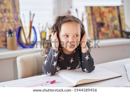 Funky child girl in headphones listening to music, happy funny girl wearing headset enjoying new audio tracks playing in digital application. Being home concept