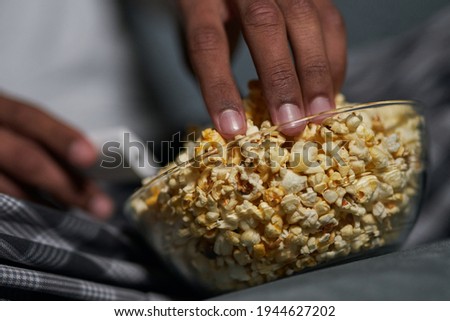 Nice taste. Close up shot of male hand taking some popcorn from a bowl