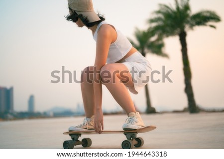 Asian Beautiful women surf skate or skateboard outdoors on beautiful summer day. Happy young women play surf skate at park near the beach on morning time. Sport activity lifestyle concept. Royalty-Free Stock Photo #1944643318