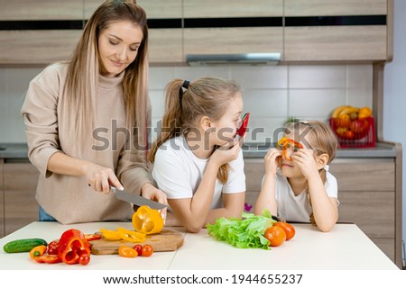 Mom and daughters are cutting ripe vegetables