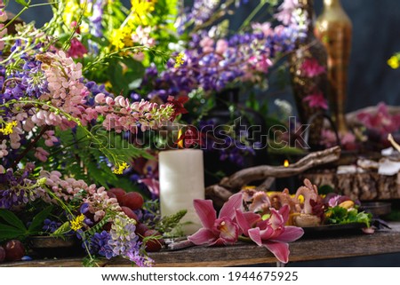 Still life in masters style. Flowers, wine, old dishes, fruits. The concept of a richly decorated table.