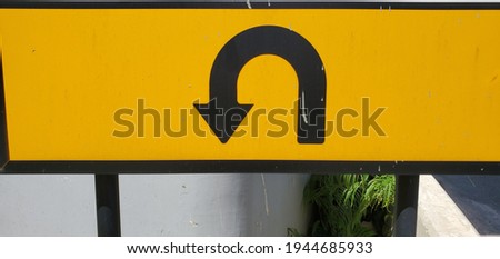 a closeup of the yellow u-turn sign on the side road