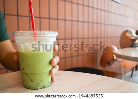 Hand on iced matcha green tea drink, stock photo