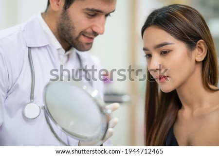 Beautician doctor wear glove and holding mirror  for female in the beauty clinic. Woman looking at her face after plastic surgery. Cosmetic treatment on her facial skin. Service and enhancement
