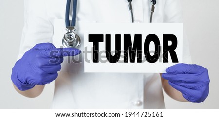 Medicine and health concept. The doctor points his finger at a sign that says - TUMOR