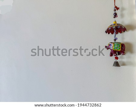 Stock photo of beautiful handmade brown colored elephant decorative item hanged on a light yellow color wall. focus on hanging elephant. Royalty-Free Stock Photo #1944732862