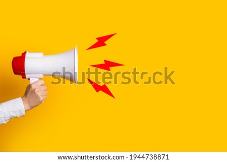 female hand holds a megaphone on a yellow background, added picture sound.