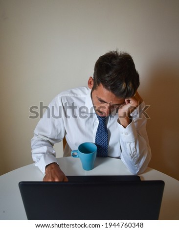 A bearded caucasian businessman working from home with a mug next to his laptop