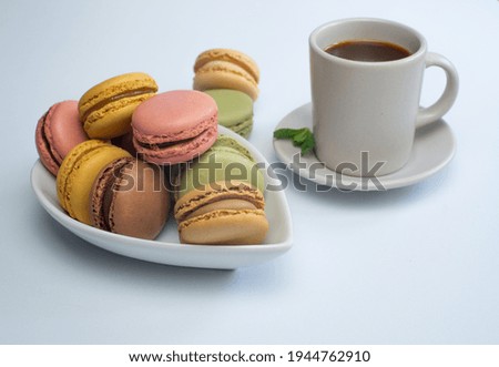 colorful macarons on white background with cup of coffee