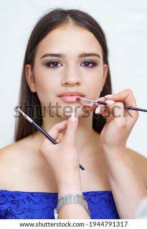 Professional makeup artist working with client in dressing room on white background