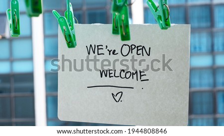 Text on vintage black sign "we're open welcome" in restaurant.