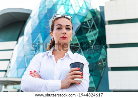 serious business woman in an urban environment holds coffee