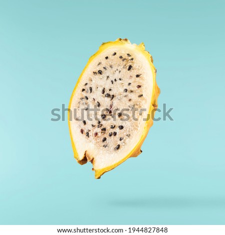 creative image with fresh yellow dragon fruit or pitaya falling in the air isolated on turquoise backround., levitation or  zero gravity food conception. High resolution image