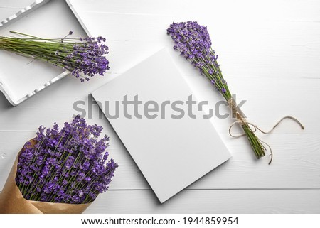 White canvas mockup and lavender flowers bouquet in tray on white wooden table background, flat lay. Blank canvas, top view