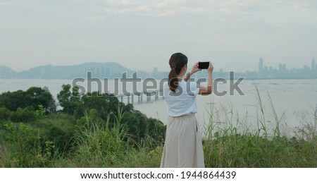 Woman uses cellphone to take photo on shore