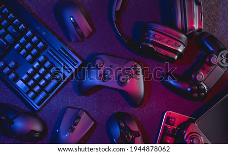 gamer work space concept, top view a gaming gear, mouse, keyboard, joystick, headset with rgb color on black table background. Royalty-Free Stock Photo #1944878062