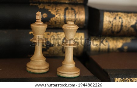 Chess pieces on a book in a library with books on the bookshelf background. Chess piece photography.  Remote offline Education, Communication with chess coach, Family.