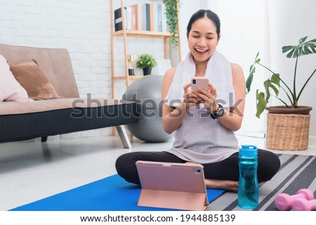 Asian woman using smartphone after play yoga and exercise at home background with copy space.Concept of relaxing exercise for healthy life.