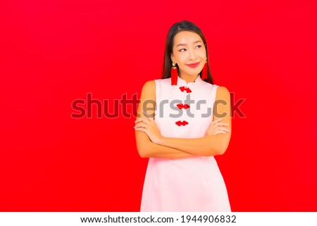 Portrait beautiful young asian woman wear chinese new year clothing on red background